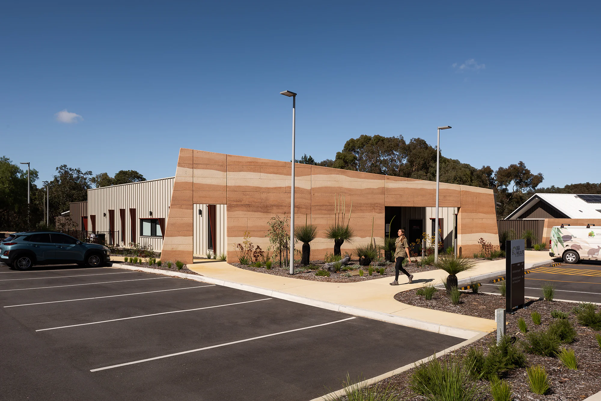 Approach to the terracotta-clad education centre with native plantings