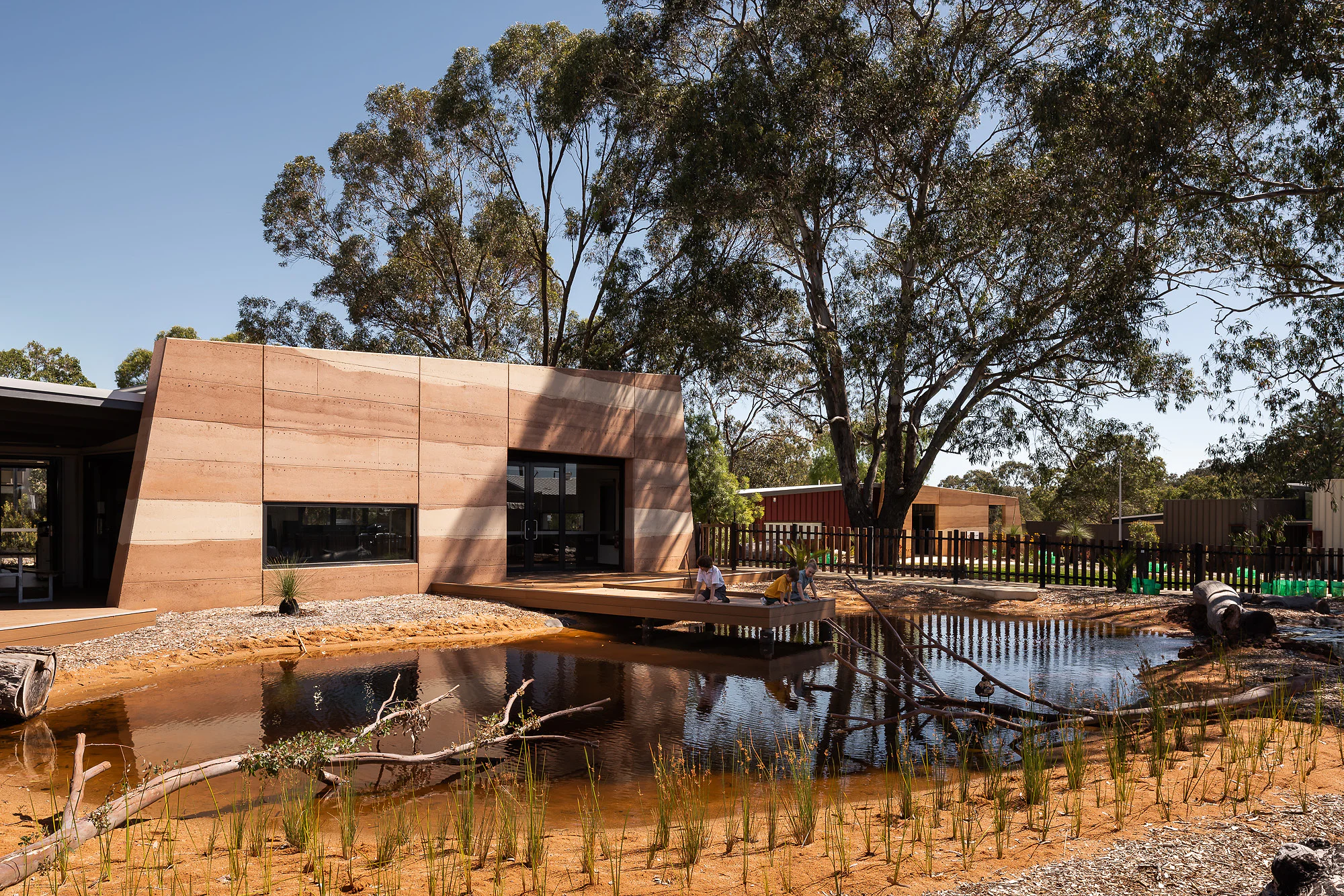 Education centre reflected in the wetland with reed plantings and viewing platform