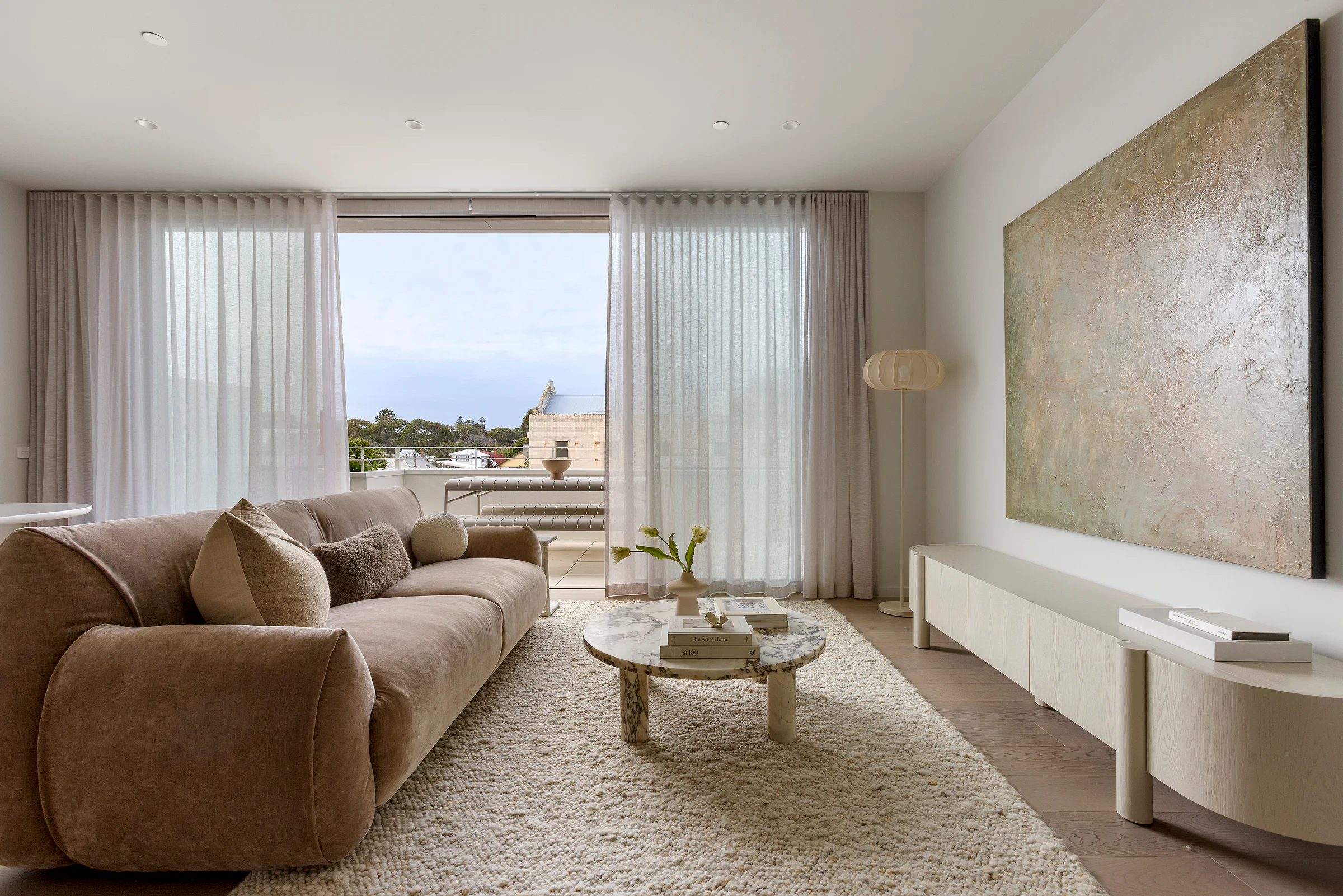 Sandringham Residences - Primary lounge with curved sofa opening to balcony