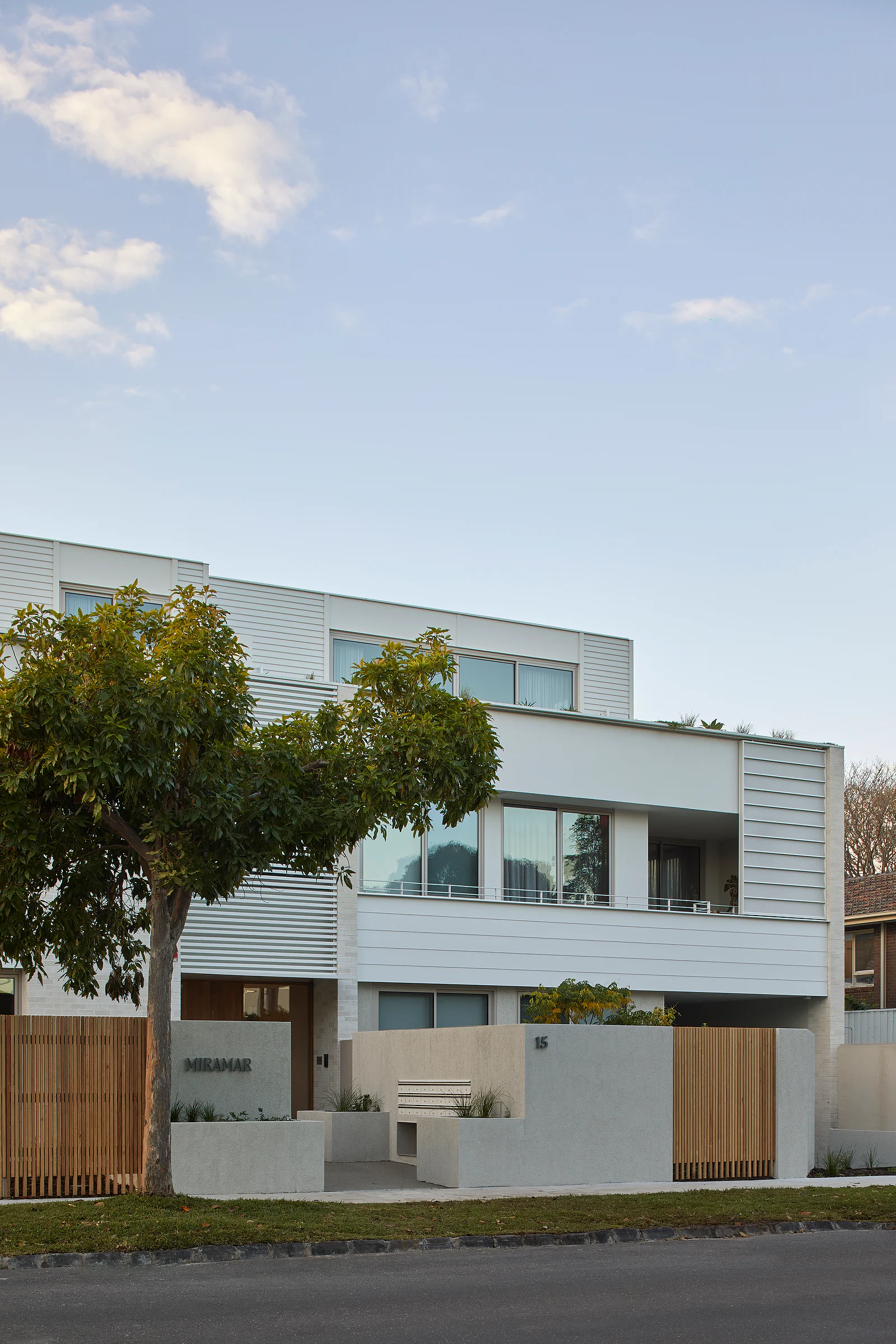 Sandringham Residences - Exterior street facade with horizontal white cladding and timber privacy screens